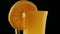 Footage of rotating glass of orange juice over dark background