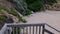 Footage of someone walking down wooden stairs leading to a beach known as Praia da Oura beach in Albufeira in Portugal on a hot