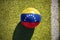 Football ball with the national flag of venezuela lies on the field