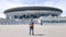 Football fan man tourist with a backpack stands and looks at the Gazprom Arena in St. Petersburg. Central stadium