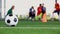 Football on green artificial turf with blurry kid soccer team training