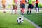 Football on green artificial turf with blurry soccer players standing