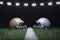 Football helmets facing off on a yard line below stadium lights