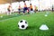 Football between marker cones on green artificial turf with blurry soccer team training