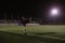 football player doing warm up exercises on the field before the match at night