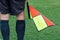 Football soccer arbiter assistant with flag at hands. Blurred green field background,