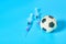 Football, soccer ball near syringe on blue background. Concept of doping in professional sport