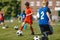 Football Summer Training Camp For School Kids. Soccer Players Running Classic Soccer Ball on Natural Grass Field