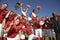 Football Team With Cheerleaders And Coach Celebrating Success On Field