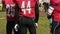 Football team players standing on field sidelines, ready to start training