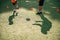 Football training concept. Shadows on the stadium grass of soccer coach trains ball kicks with young football players.