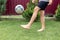 Footballer barefoot stuffs the ball on the green grass.