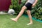 Footballer barefoot stuffs the ball on the green grass.