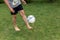 Footballer barefoot stuffs the ball on the green grass.