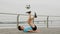 Footballer is juggling ball with feet lying on back on waterfront in city.