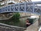 Footbridge crossing the canal in brighouse west yorkshire with an old green narrow boat moored next to the towpath