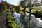 Footpath alongside the Cromford Canal in Derbyshire, England, UK. Trees with autumnal colours reflected in calm waters.