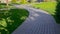 Footpath of paving slabs on which close-up of feet of walking people in city pictorial park with green lawns