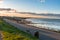 Footpath on a sewall along a sandy beach at sunset