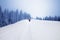 Footpath in snow and hikers going up on snowy slope