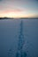 Footprint snow track at wintry field, sunset scenery