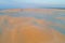 Footprints across sand dunes glowing in orange sunrise.