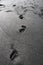 Footprints on the beach on black volcanic sand.