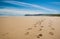 Footprints of hiking boots on the sand of a remote beach