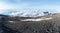 Footprints lead off through volcanic ash and dust towards a glacier sitting above the clouds on the summit of Mount Kilimanjaro