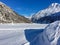 Footprints reaching across frozen lake with mountains