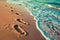 Footprints on sandy beach being washed away, transient imprints