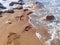 Footprints in the sea sand. A foaming wave rolls ashore. Sea surf. Powerful waves. Storm at sea. Selective focus