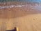 Footprints and small sand castle on the empty beach - calm small waves