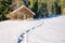 Footprints in snow leading to old wooden cabin and forest. Allgau, Bavaria, Germany, Alps.