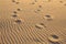 Footprints on the wavy golden sand beach. Abstract.