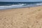 Footprints on Wide Stretch of Beach with Deep Blue Sea