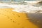 Footprints on the yellow sand flooded with sea waves