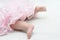 Foots of newborn baby in pink dress dancing