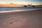 Footsteps in the sand at sunrise on empty beach