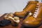 Footwear Concepts and Ideas. Closeup of Premium Male Brogue Tanned Boots with Lots of Cleaning Accessories on Foreground.