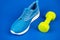 footwear for training with dumbbell on blue background, sport accessory