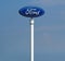 Ford logo in the dealership of the area, against blue sky. It is the symbol of the american vehicle manufacturer