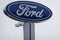 The Ford Motor Company logo as seen isolated on a tall sign at a car dealership. Ford`s headquarters are in Dearborn, Michigan