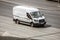 Ford Transit Fourth generation in the city street. Aerial side view of white light commercial vehicle in motion