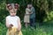 In foreground girl holding a flower. In background parents embracing each other looking at her