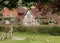 In foreground, graves in grounds of St Mary the Virgin Church in Turville in The Chilterns, with characterful houses behind.
