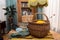 In the foreground knitted socks and a wicker basket on a table covered with a folk blanket, vintage interior in a defocused