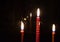 In the foreground unfocused three burning candles.They are reflected in the window glass