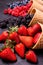 In the foreground, variety of fresh berries in ice cream cones