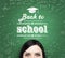 A forehead of the girl and words: \' back to school \' which are written on the green chalkboard.